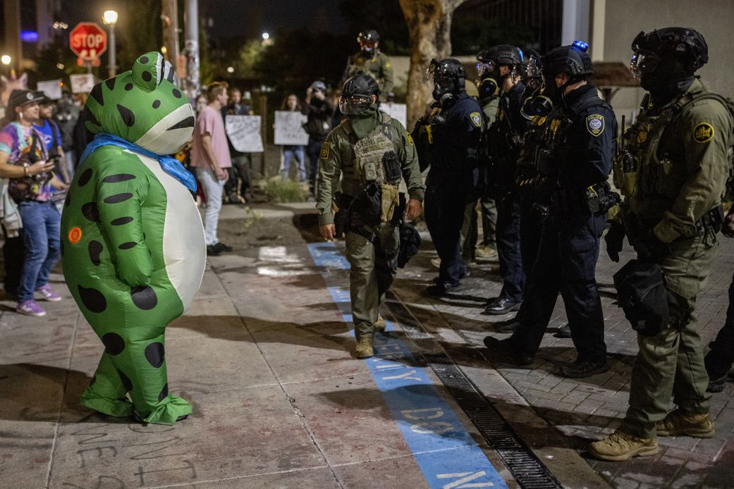 Frog protester facing line of federal agents at night