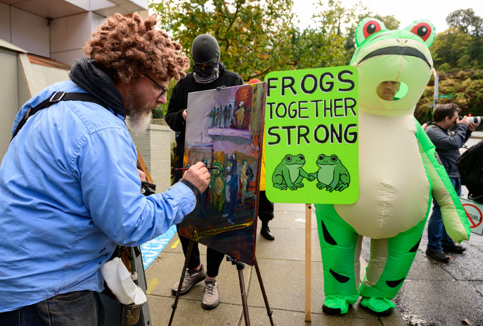 Frogs Together Strong protester with artist painting the scene